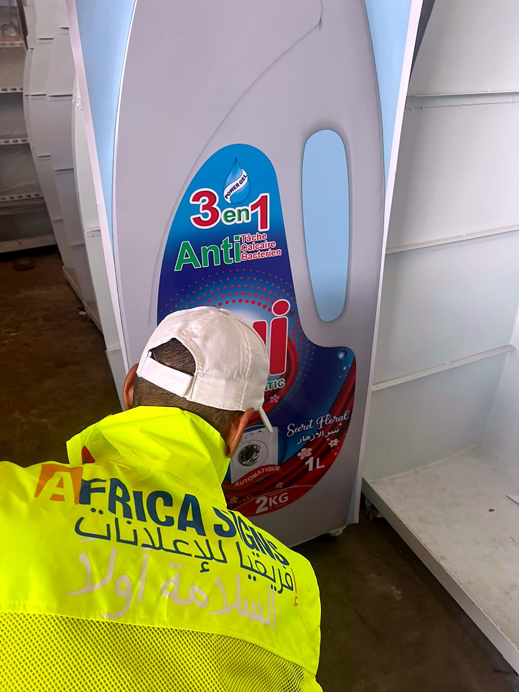 Technicien Africa Signs finissant un présentoir en forme de bouteille ONI